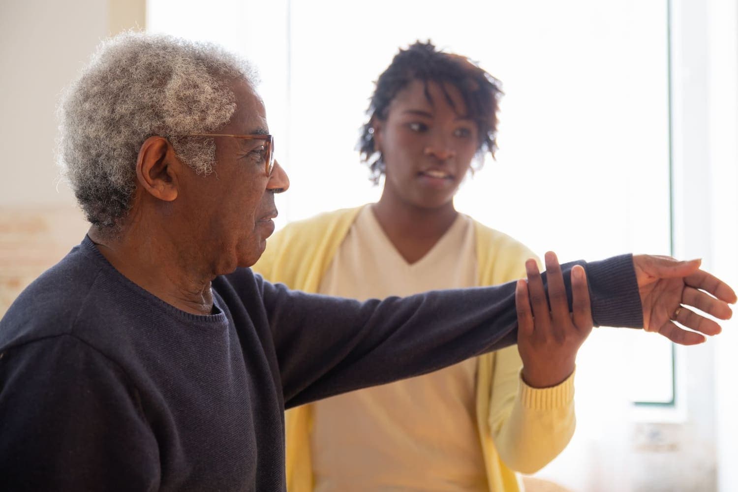 Domiciliary care worker helping an older man with gentle exercises in his own home