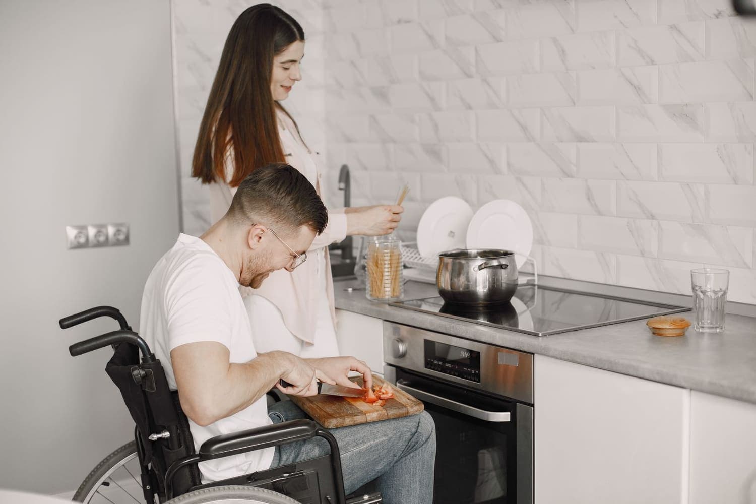 Support worker cooking alongside a wheelchair user in a supported living kitchen