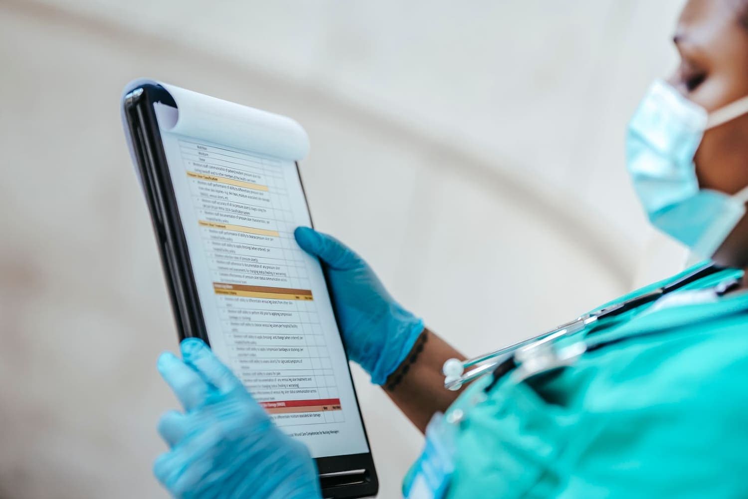 Care worker in uniform reading a printed policy and procedure document during induction