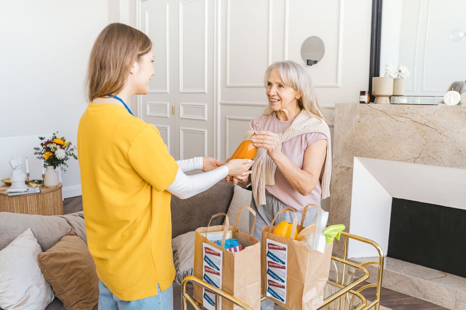 Home care worker bringing shopping to an older woman at home, the service most new CQC registrations cover